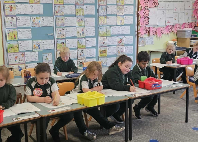 kindergarten student working at desks in colourful classroom